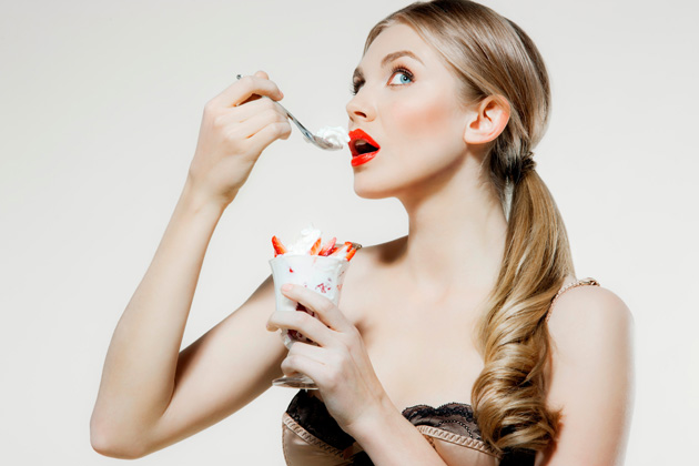 Young woman eating strawberries and cream